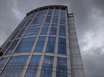 Low angle view of modern building against cloudy sky