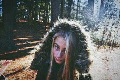 Portrait of confident girl wearing fur hood in forest