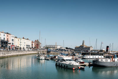 Sailboats moored at harbor against clear sky