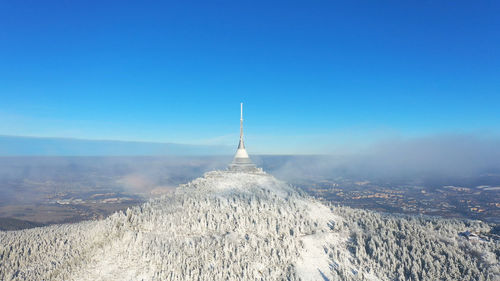 Aerial view of snowcapped mountain against blue sky