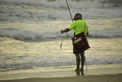 Rear view of man working on beach