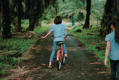 Rear view of man with bicycle on road