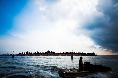 Man driving motorboat in grand canal against cloudy sky