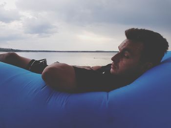 Man relaxing in sea against sky