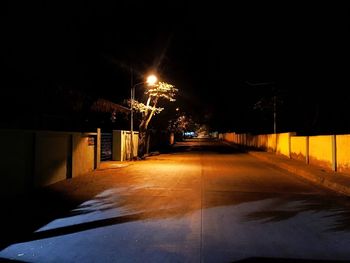 Empty road along illuminated street lights at night