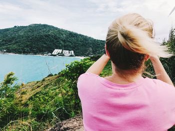Rear view of woman looking at waterfall against sky