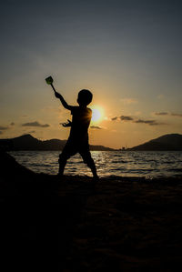 Silhouette man playing at beach during sunset