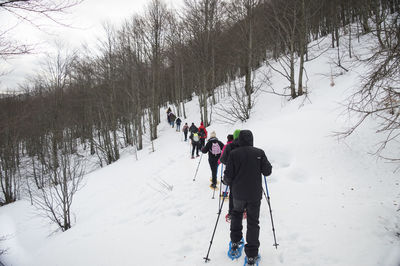 Rear view of people walking on snow covered mountain