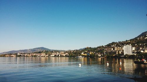 Scenic view of river by town against clear blue sky