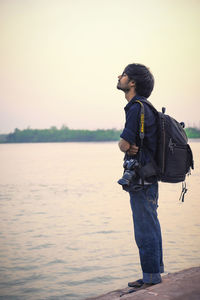 Side view of man looking at lake against sky