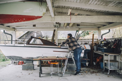 Mature man repairing speedboat in garage