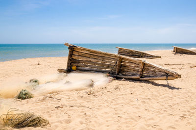 Traditional wooden fishing boats on beach against blue sky, lobito, angola