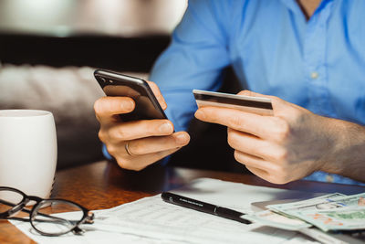 Midsection of man using smart phone on table