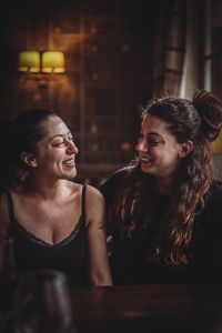 Lesbian couple smiling while sitting face to face at home