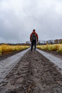 Rear view of man standing on road against sky