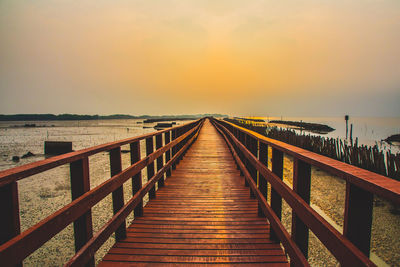 Pier over sea against sky during sunset