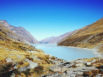 Scenic view of lake and mountains against clear blue sky