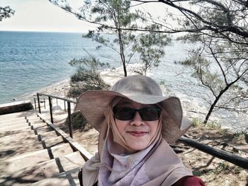 Portrait of woman standing o staircase against sea