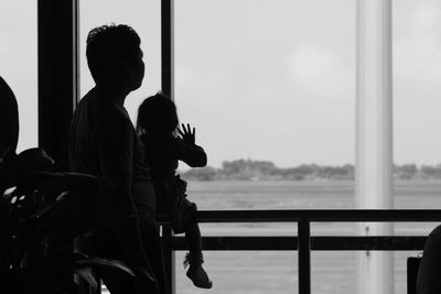 Rear view of man and woman standing by window