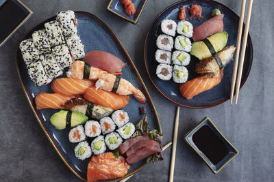 The range of different types of sushi, rolls and maki with sauces and chopsticks.