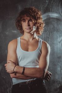 Portrait of beautiful young woman standing against wall