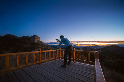 Man standing on footbridge against clear blue sky
