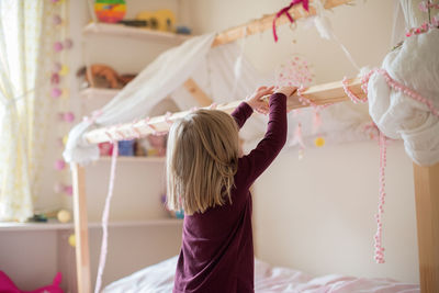 Rear view of girl playing with lace at home