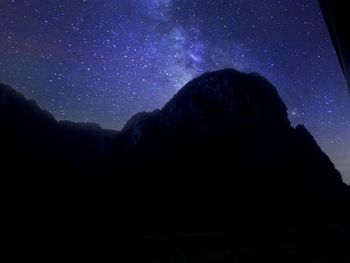 Low angle view of silhouette mountain against sky at night