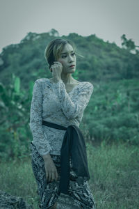 Portrait of young woman standing on field