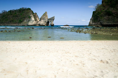 Rock formations on beach against sky