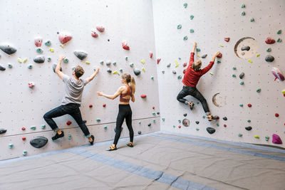 Instructor training male and female students rock climbing in gym