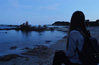 Rear view of woman on beach against sky