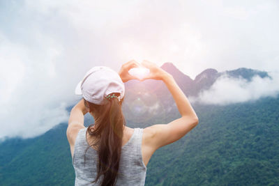 Rear view of woman sitting on mountain against sky