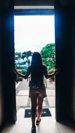 Rear view of woman standing by window