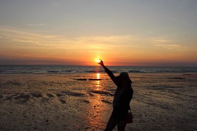 Silhouette people at beach against sky during sunset