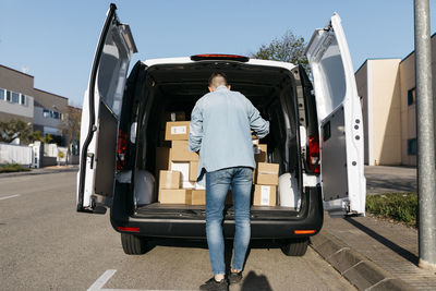 Man standing near packages in delivery van