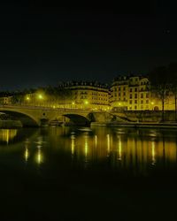 Illuminated bridge over river against sky at night