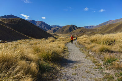 Rear view of woman walking on mountain against sky