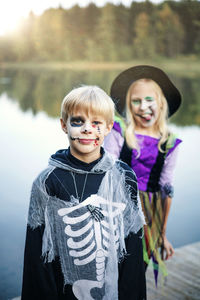 Happy halloween sibling kids have fun in carnival costumes against the lake
