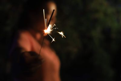 Midsection of woman with fire crackers in the dark