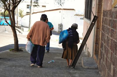 Rear view of men walking on sidewalk in city