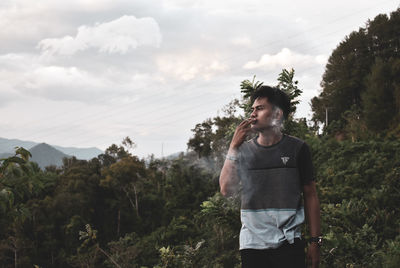 Young man standing against plants and trees