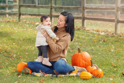 Mother carrying cute daughter while sitting on grassy land