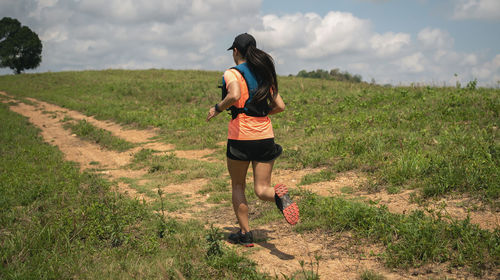 Rear view of woman running on field