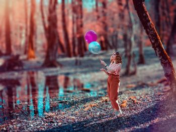 Full length of person with balloons in forest