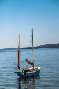 Boat sailing in sea against clear blue sky