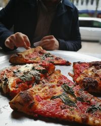 Close-up of hand holding pizza on table