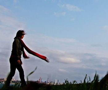 Side view of man standing on field against sky