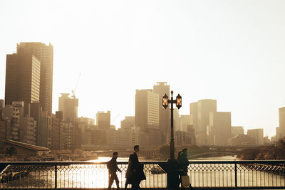 People against buildings in city during sunset