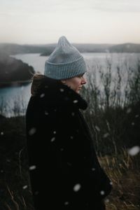 Side view of woman standing on mountain during winter